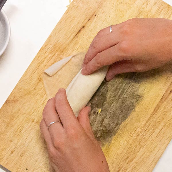 Folding the spring roll up to the top corner.
