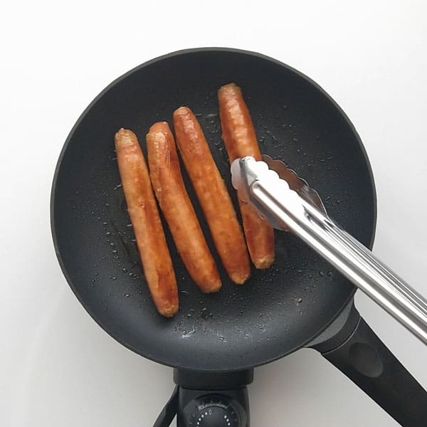 Cooking beef sausage in a frypan.