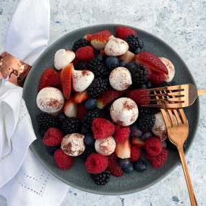 A bowl of fresh berries with sumac dusted mini meringues.