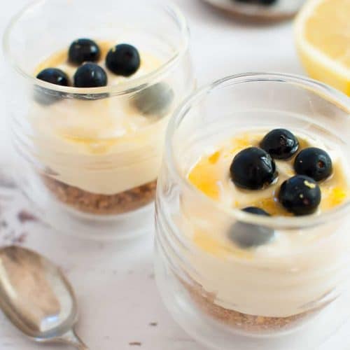 Three cups of lemon cheesecake decorated with fresh blueberries