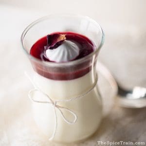 Glass jar filled with Bavarian cream topped with berry syrup.
