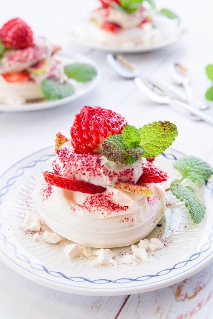 Close up shot of eton mess, showing the meringue base topped with fresh cream, strawberries, kiwi fruit and mint.