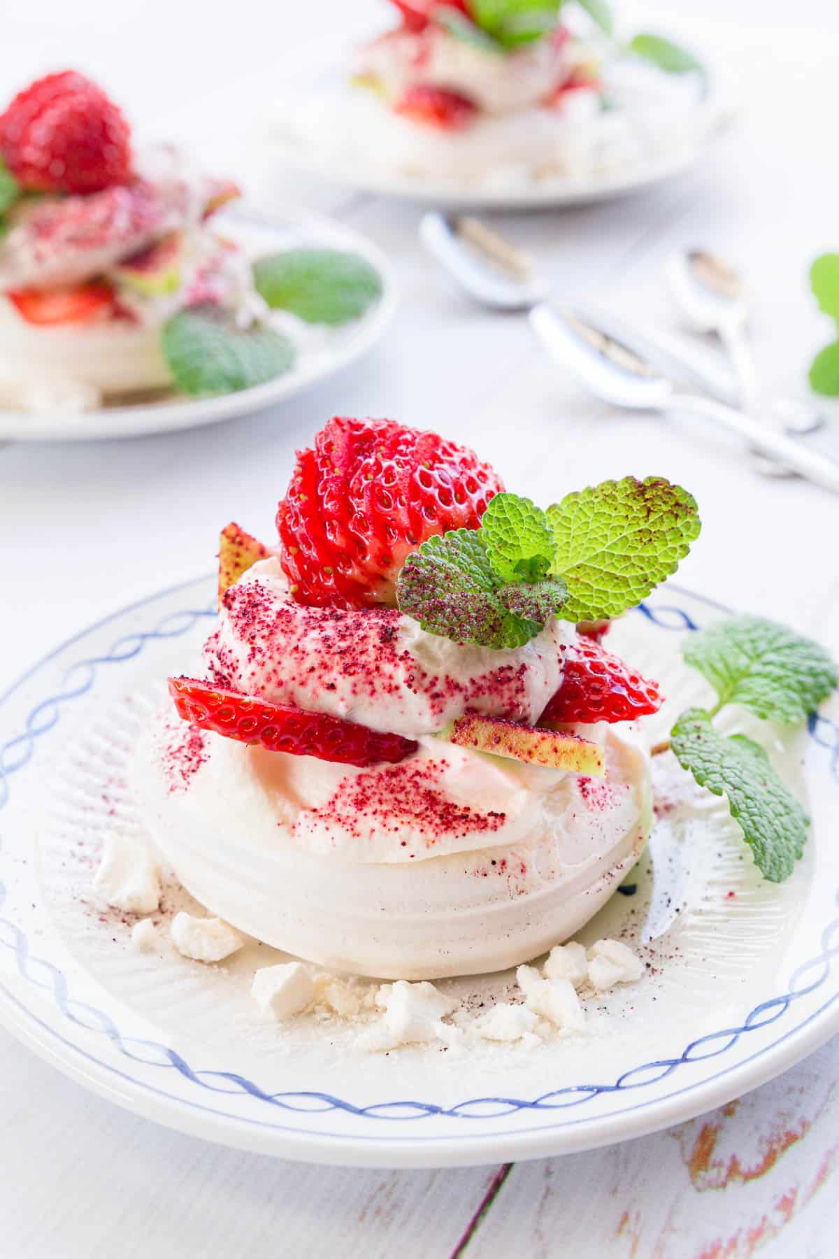 Close up shot of eton mess, showing the meringue base topped with fresh cream, strawberries, kiwi fruit and mint.