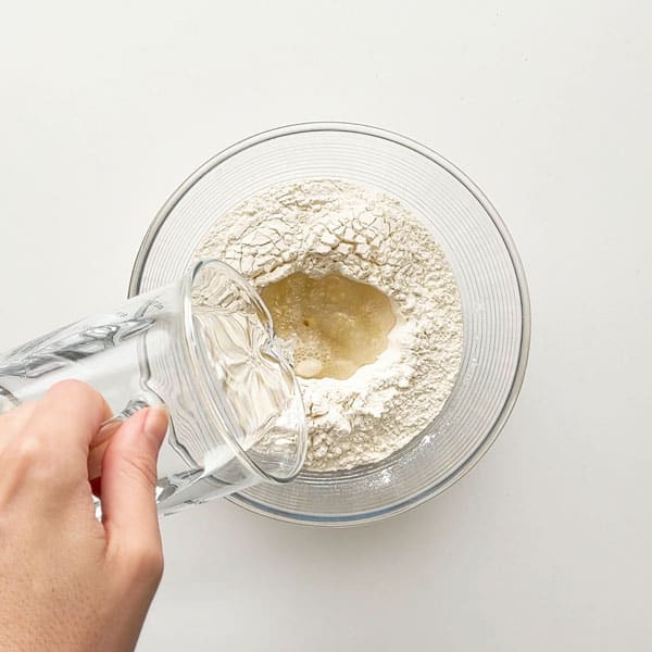 Pouring water into pizza dough.