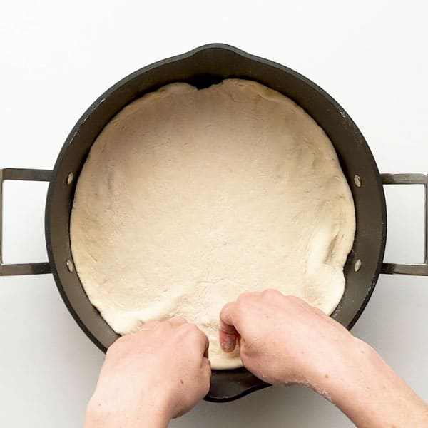 Placing the pizza dough into the pan.