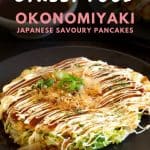 Okonomiyaki pancake on a black plate smothered in sauce.