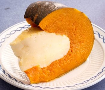Pumpkin filled with coconut custard on a white plate.