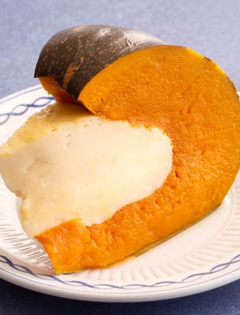 Pumpkin filled with coconut custard on a white plate.