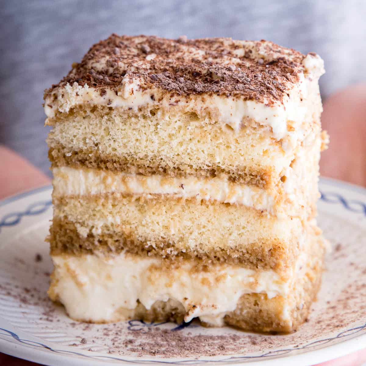 Close up shot of tiramisu showing three layers of coffee soaked biscuits and whipped cream.