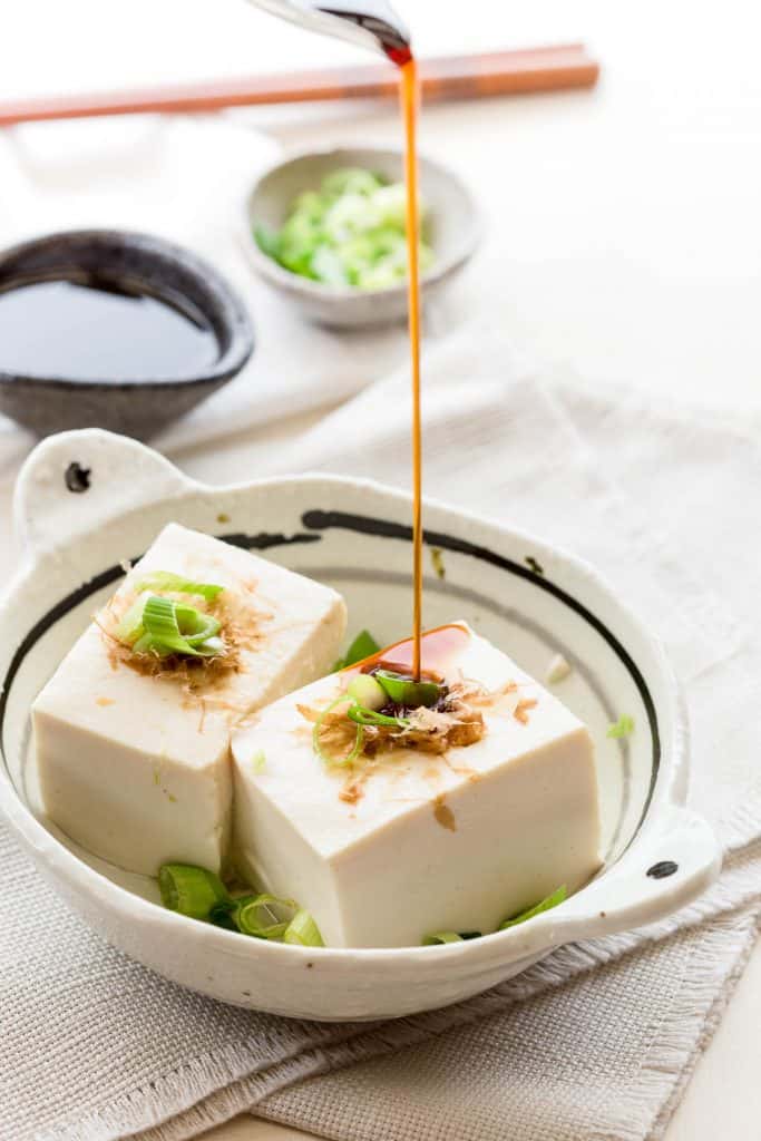 Pouring mentsuyu sauce over hot simmered tofu
