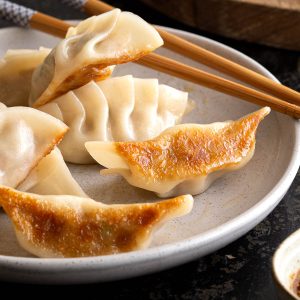 Crispy gyoza on a plate with dipping sauce.