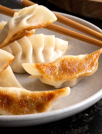 Crispy gyoza on a plate with dipping sauce.