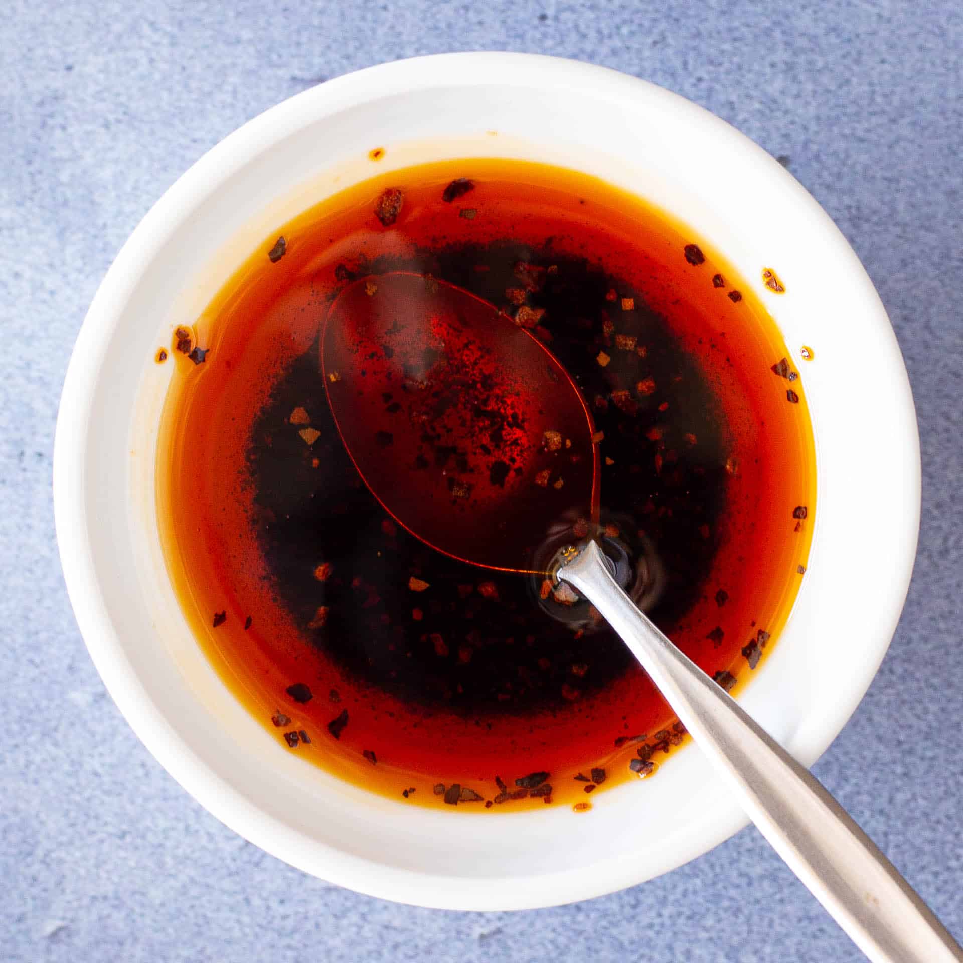 Spicy chilli oil in a white dish with a spoon.