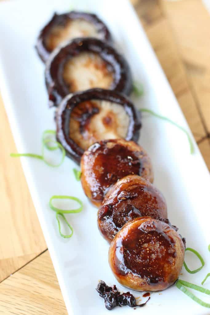 Sticky soy mushrooms on a white plate with garnish.