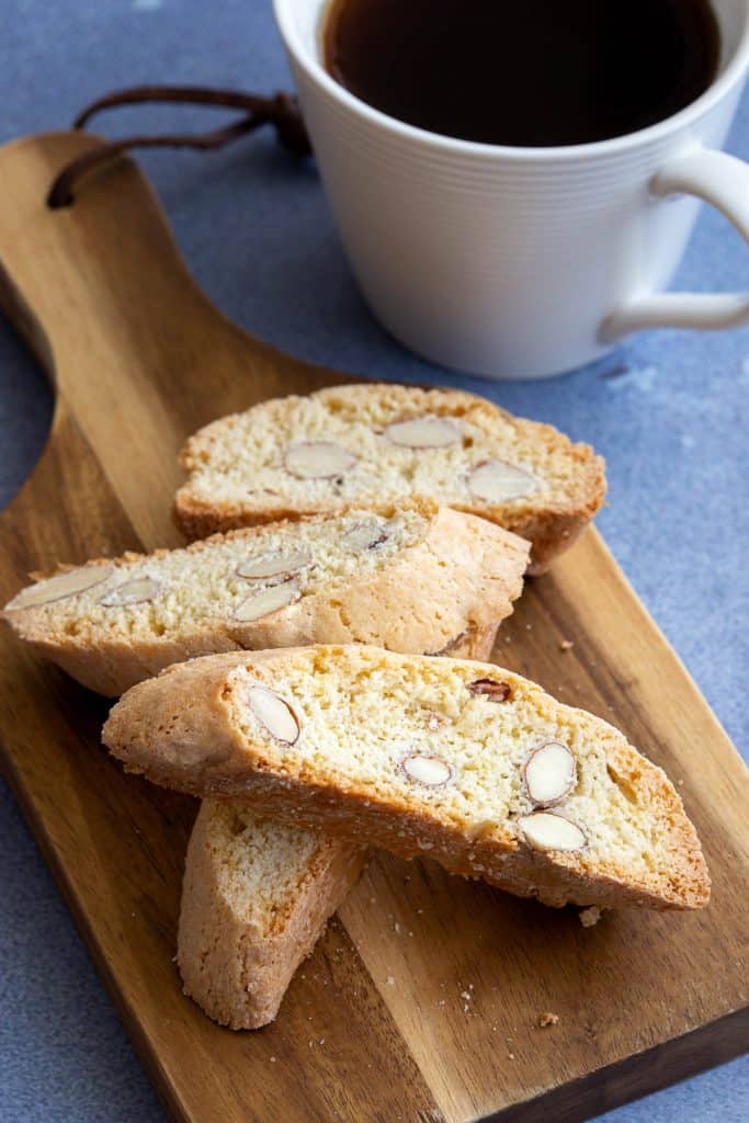 Small wooden board with cantucci toscani and mug of coffee.
