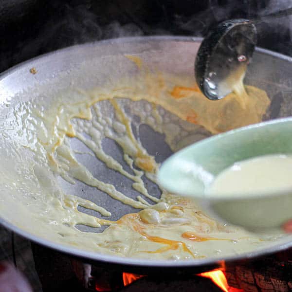 Ladling the egg batter into the wok.