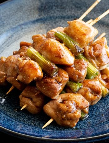 Blue plate with a stack of yakitori chicken skewers.