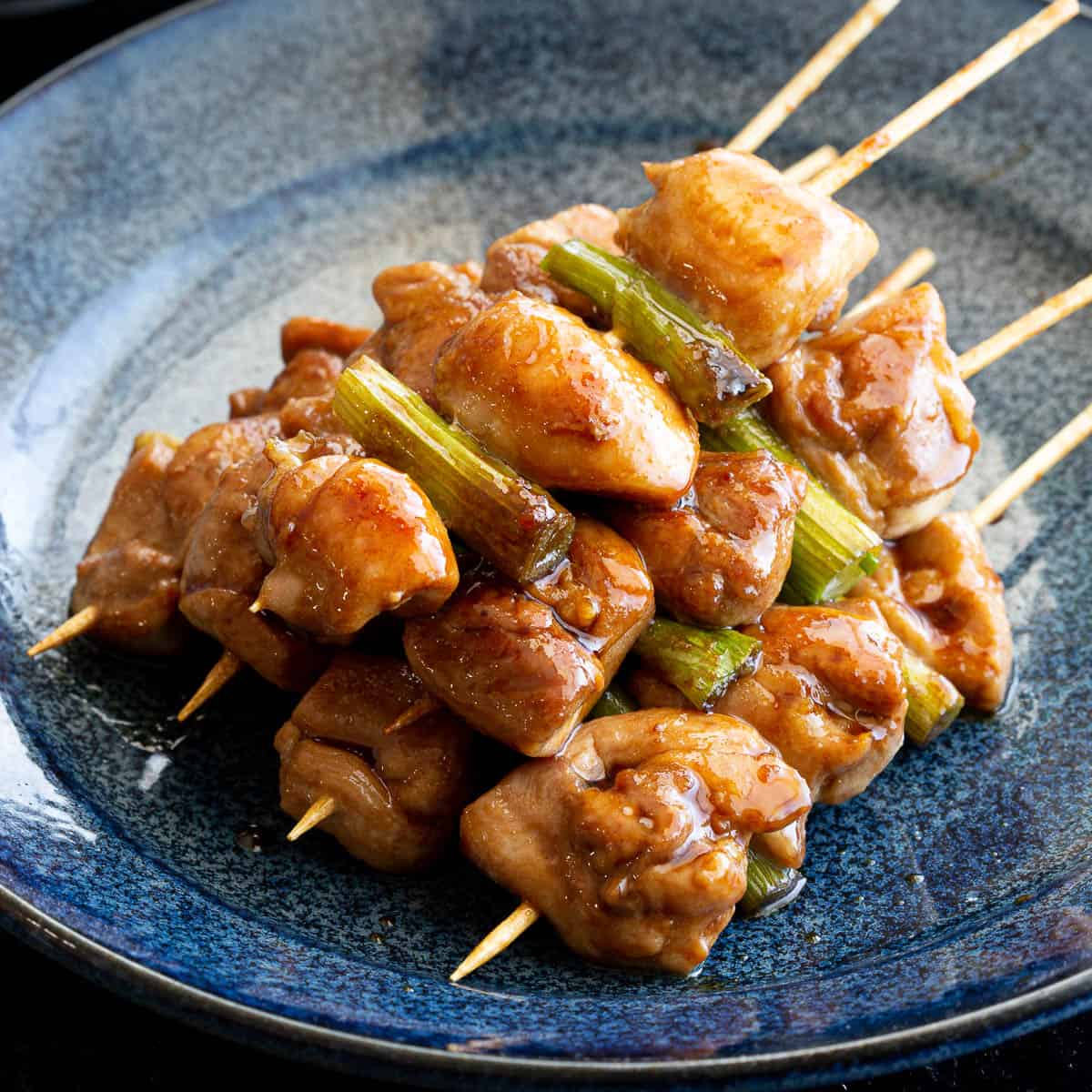 Blue plate with a stack of yakitori chicken skewers.