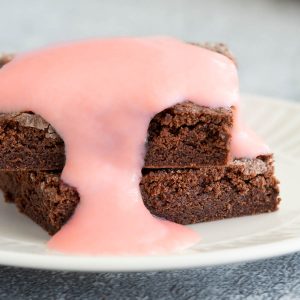 A stack of chocolate concrete cake smothered in pink custard.