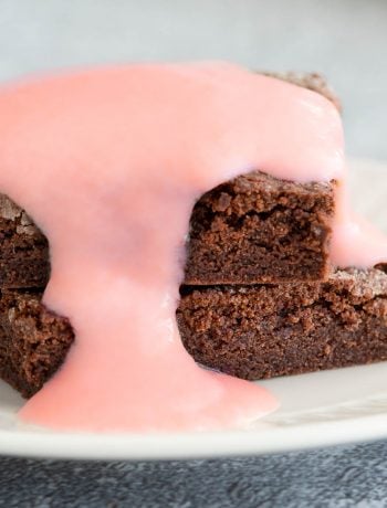 A stack of chocolate concrete cake smothered in pink custard.
