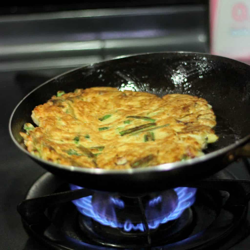 The Korean pancake has now been flipped, showing that the bottom was cooked until golden and crispy.