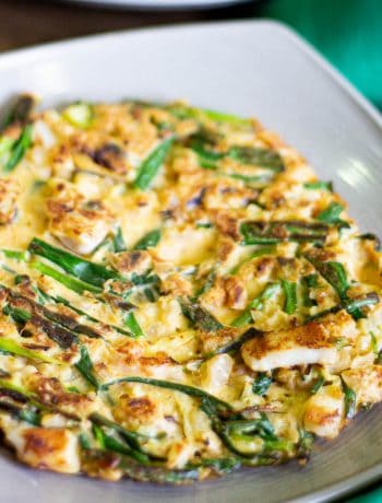 Close up shot of a Korean haemul pajeon pancake showing the crispy fried batter and green onions.