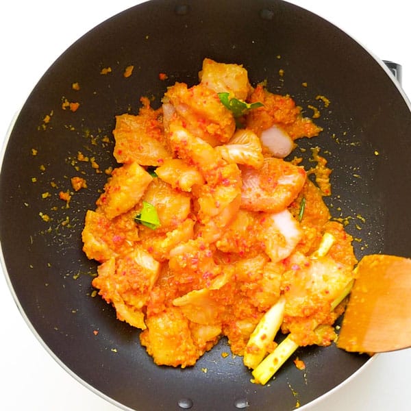 Stir frying fish pieces in curry paste.