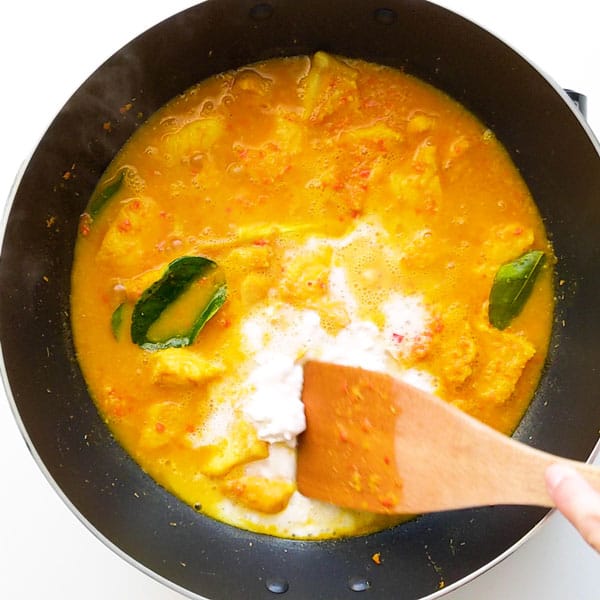 Adding coconut milk into the Indonesian fish curry.