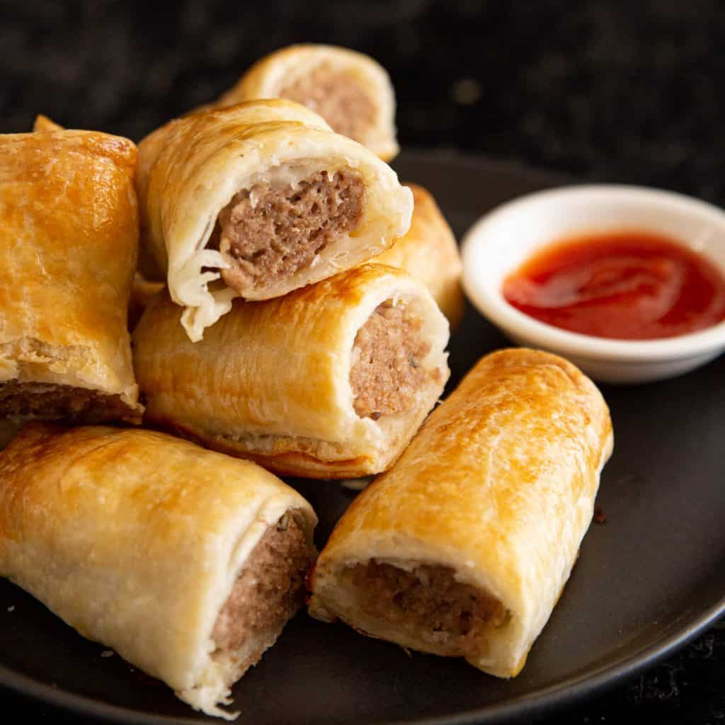 Close up of sausage rolls with tomato sauce.