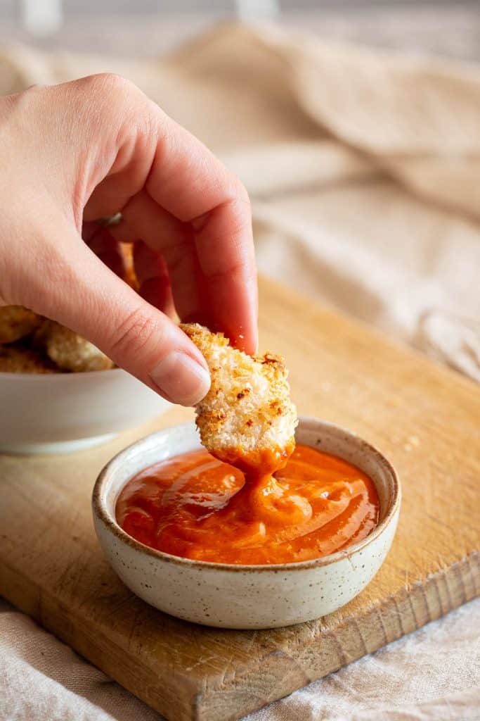 Dipping an air-fried popcorn chicken into our gochujang mayo sauce.