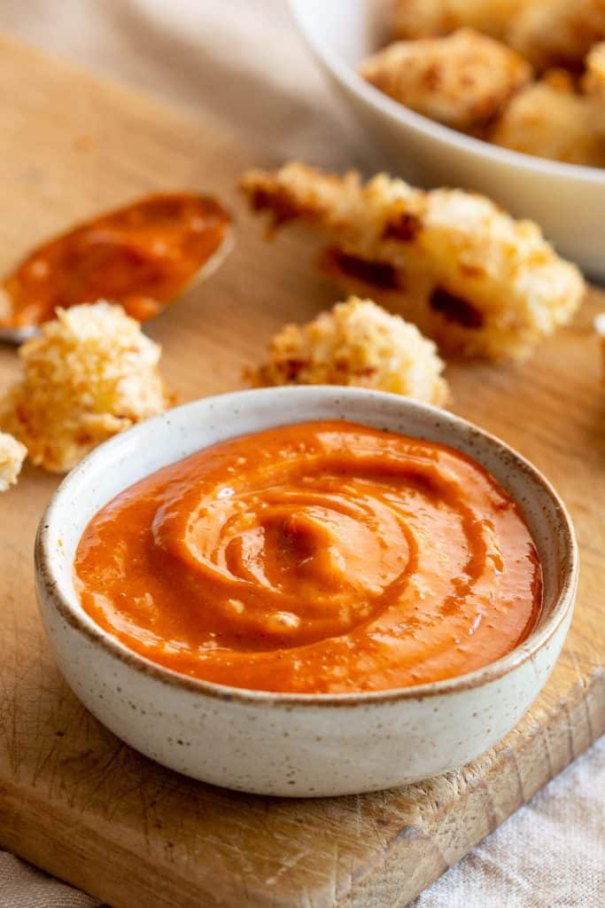 Gochujang dipping sauce in a small dish, surrounded by popcorn chicken.