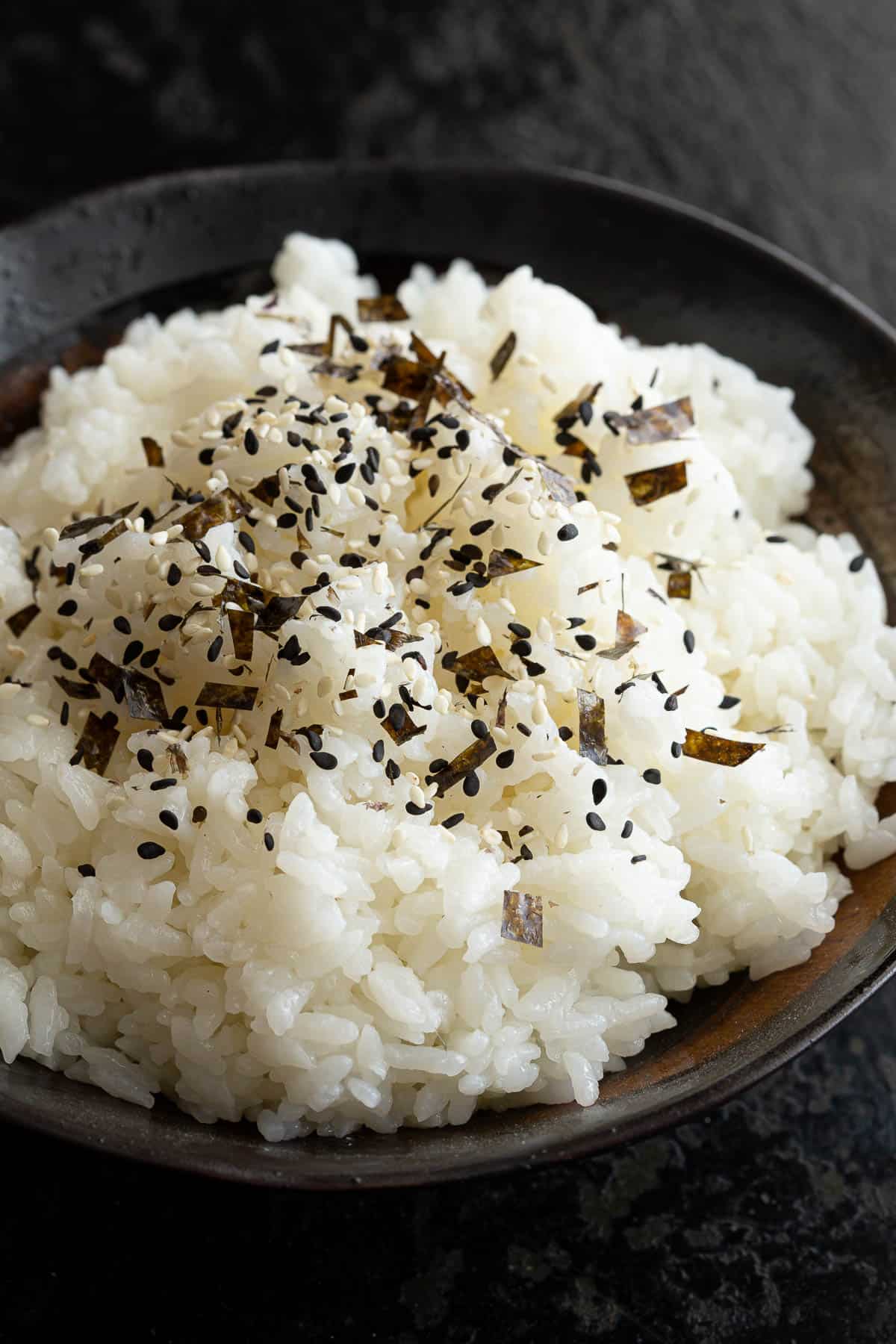 A bowl of cooked rice sprinkled with furikake rice seasoning.