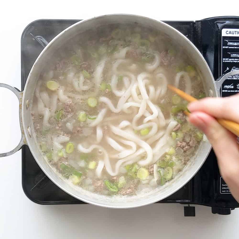 Breaking apart udon noodles with chopsticks.
