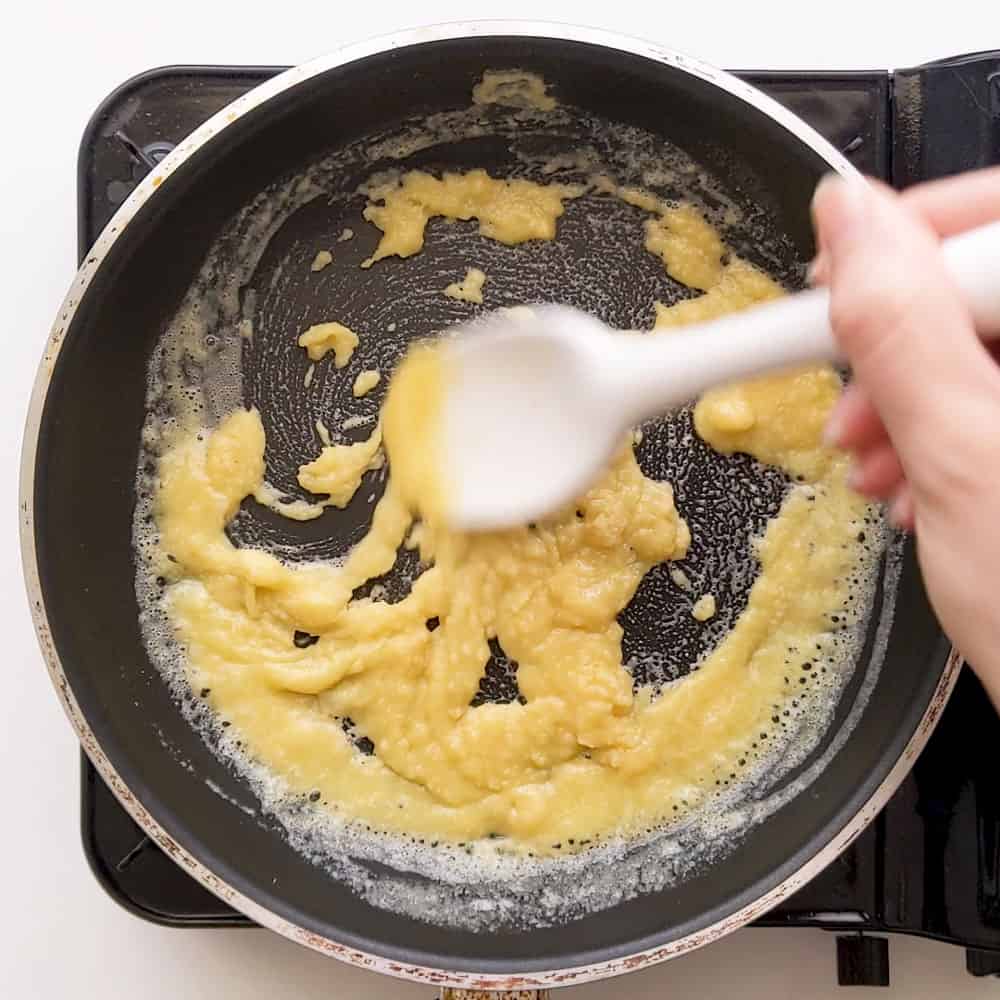 Using a spoon to combine the melted butter with the flour.