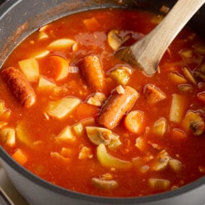 Sausage and bean casserole in Remoska with wooden ladle.