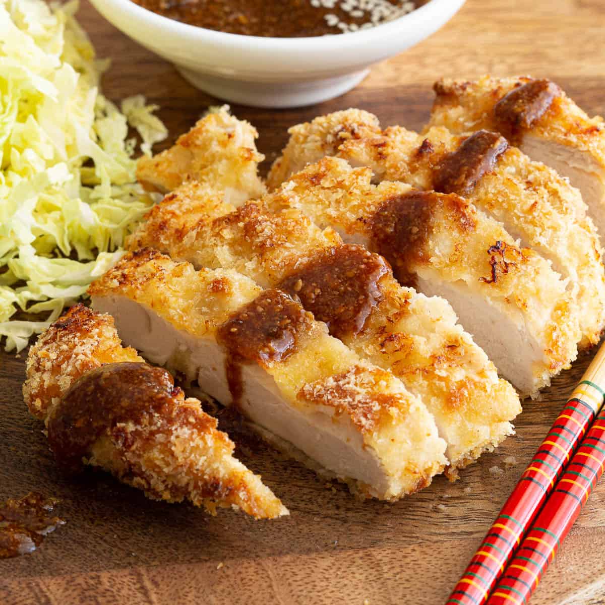 Panko crumbed katsu chicken with chopsticks, cabbage and tonkatsu sauce.
