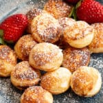 Dutch mini pancakes on a plate with strawberries.