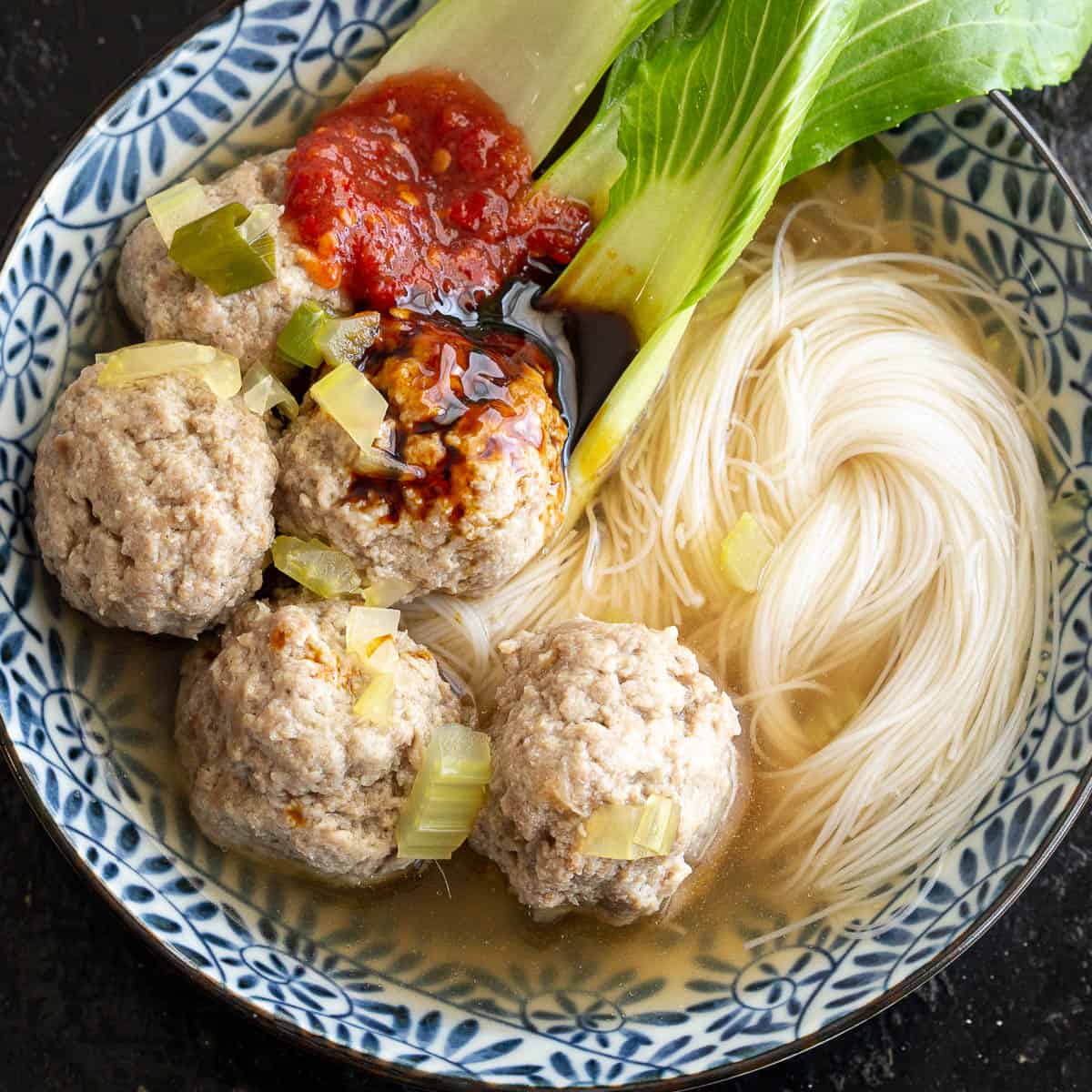 Beef meatballs in a soup broth with noodles and bok choy.