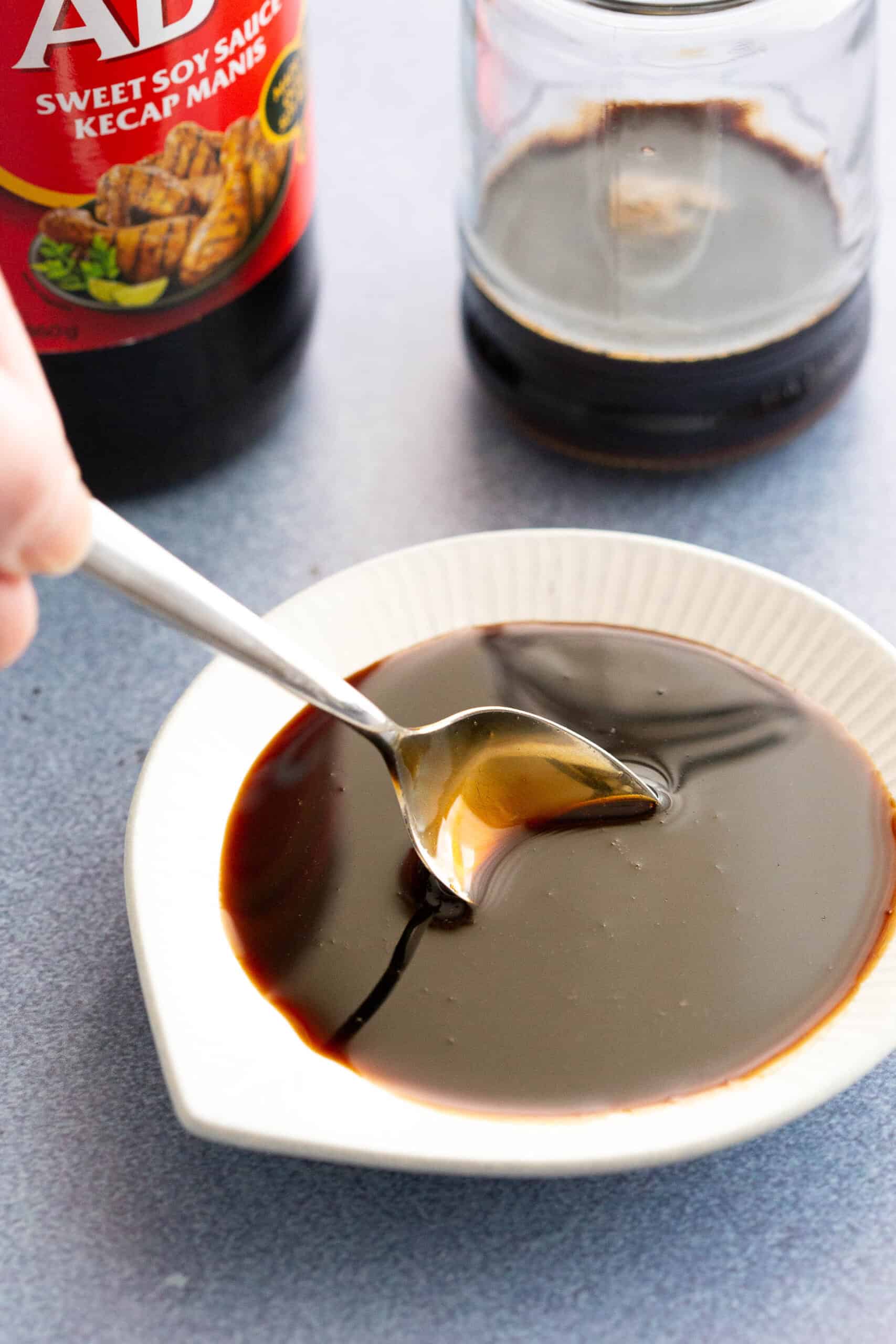 Dipping a spoon into homemade Indonesian sweet soy sauce.