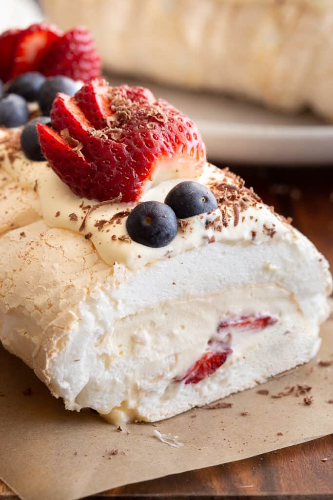Meringue roulade stuffed with berries on baking paper.