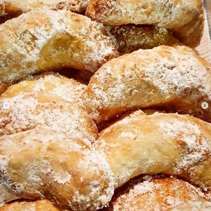 A pile of almond crescent cookies dusted with icing sugar.