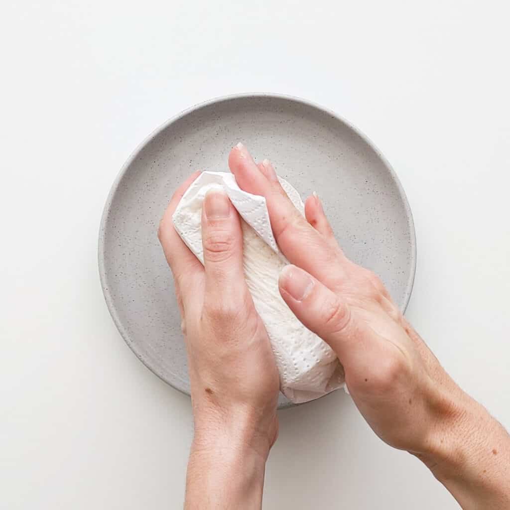 Wiping moisture off tofu with a paper towel.