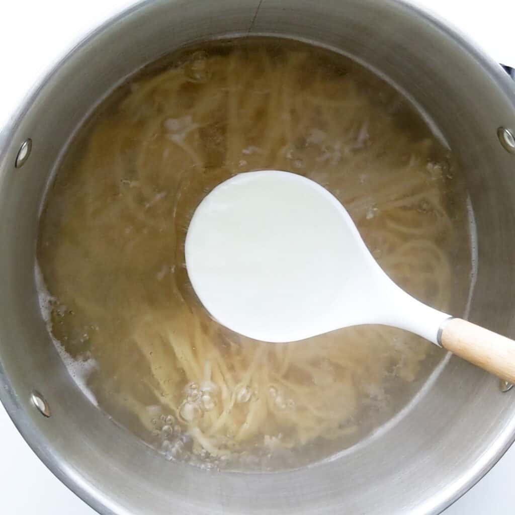 Scooping pasta water out to use in the sauce.