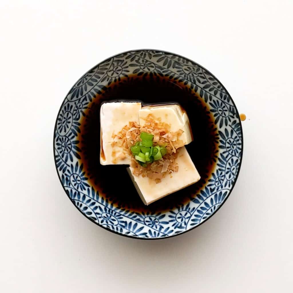 Bowl of fresh yudofu topped with bonito flakes and spring onion.