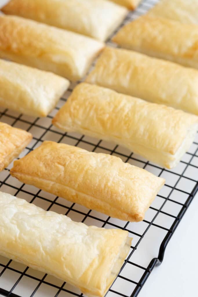 Puffed pastry cooling on a black rack.