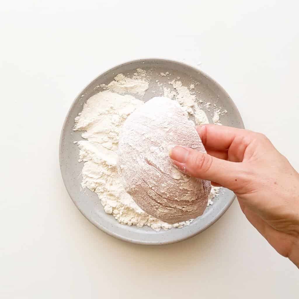Coating chicken in flour.