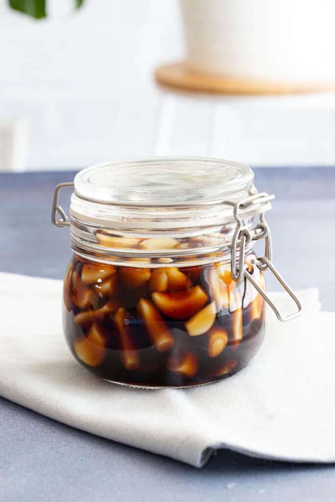 A jar of freshly made Korean Pickled Garlic on a light blue tea towel.