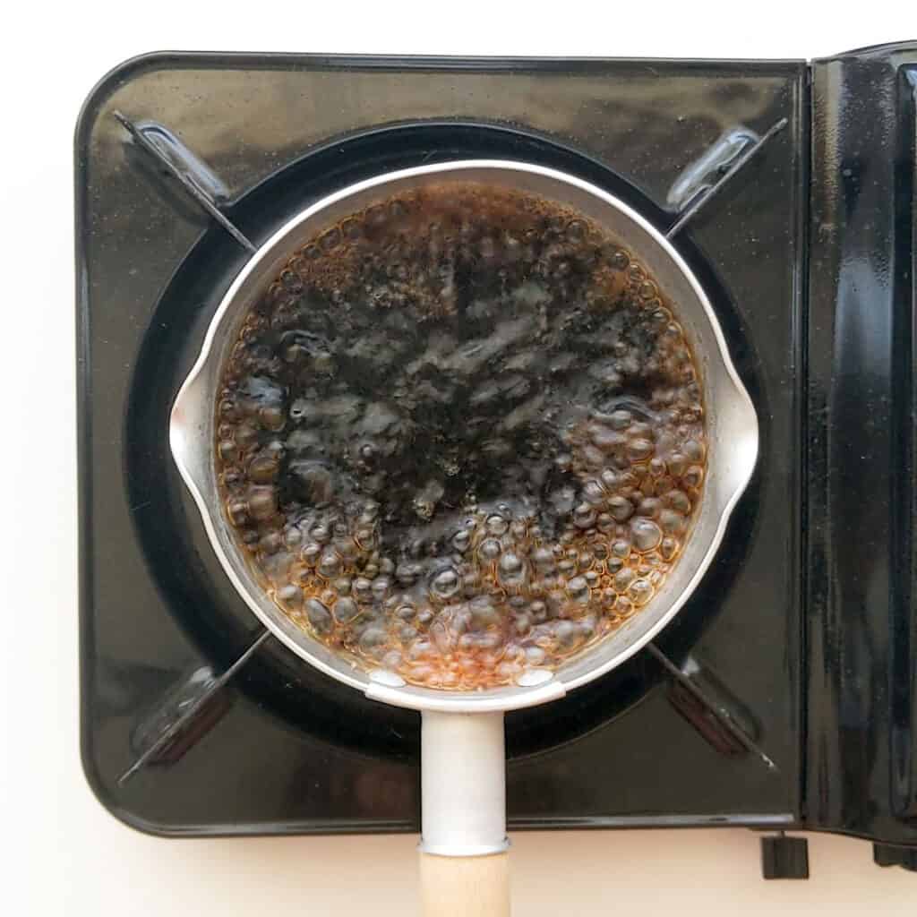 Boiling pickling liquid with soy sauce in a small saucepan.