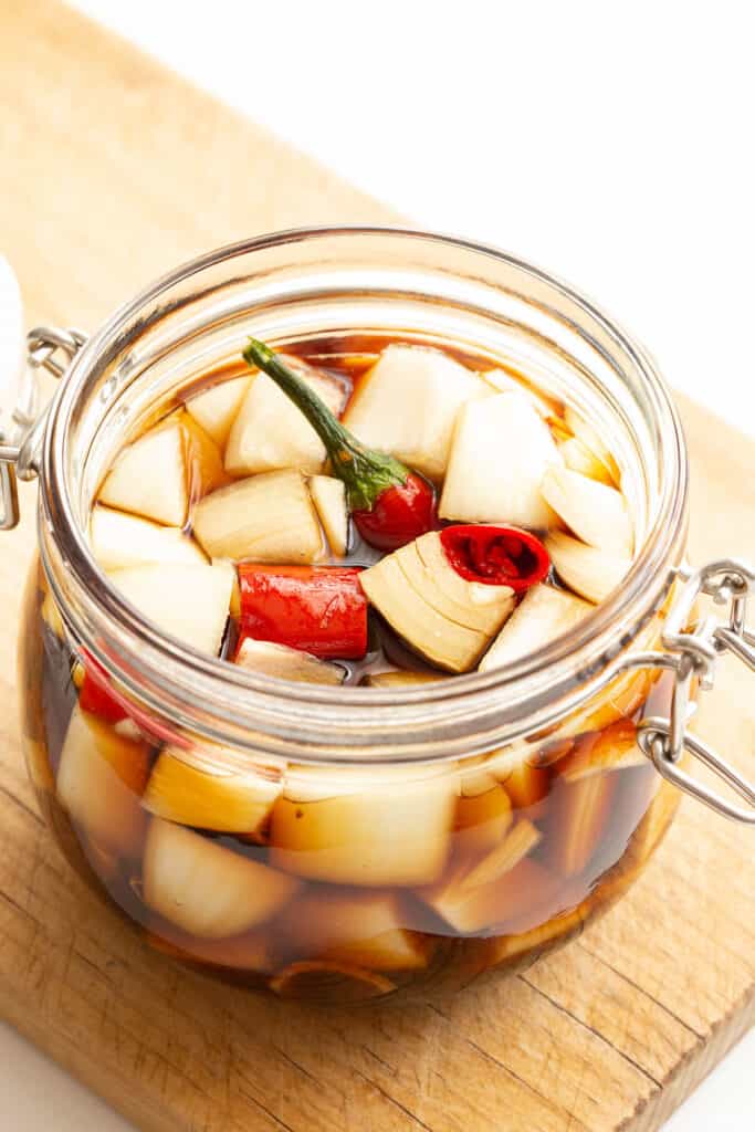 A glass jar full of Korean pickled onion with chilli.