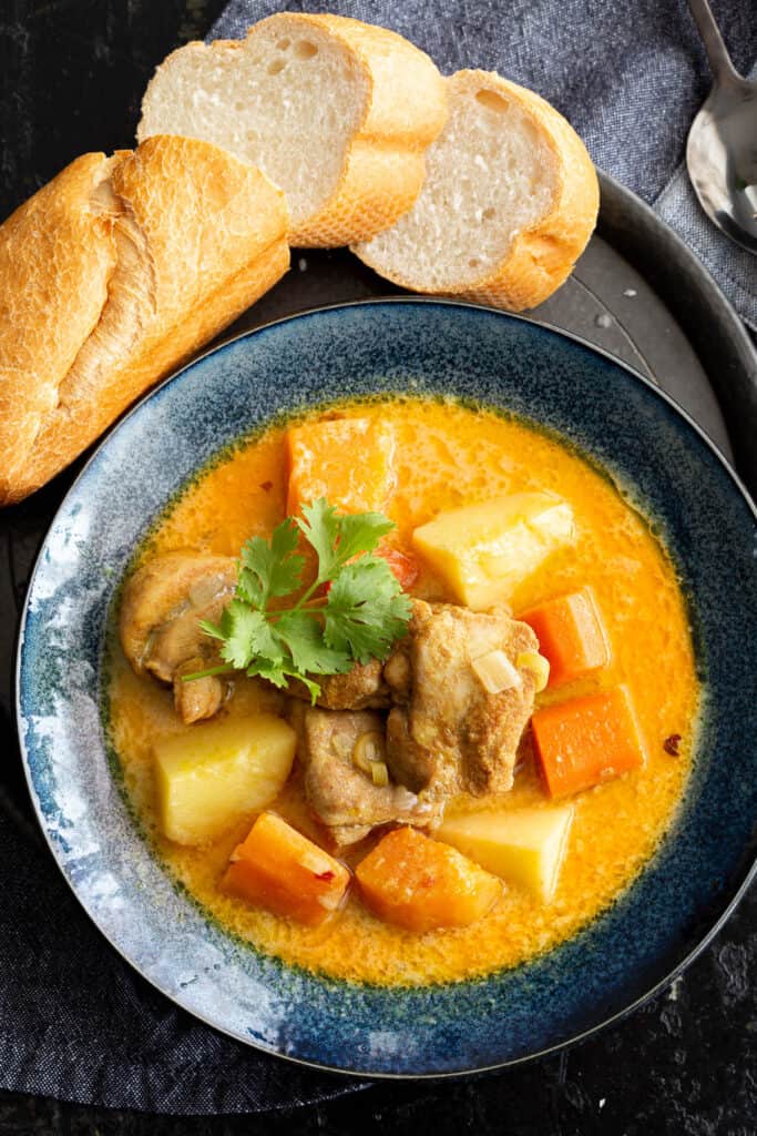 A bowl of Vietnamese curry with a side serve of crusty bread.